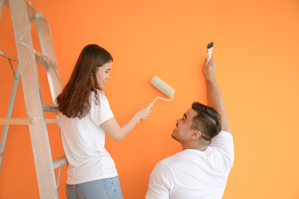 ผู้หญิงและผู้ชายช่วยกันทาสีภายในบ้าน โทนสีส้ม